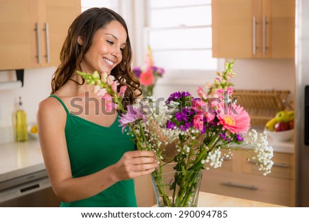 Beautiful woman arranging flowers picked from her garden at home happy and joyful