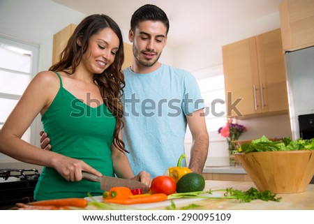 Happy healthy young vegan couple cooking vegetables at home