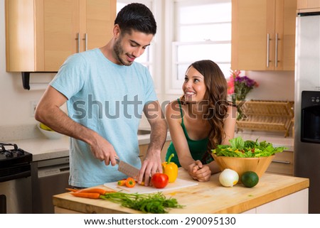Handsome chef man and beautiful woman on a date chopping vegetables and a nutritious meal and salad