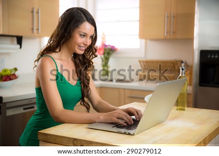 Happy lady typing on her laptop computer while relaxing at home with perfect smile