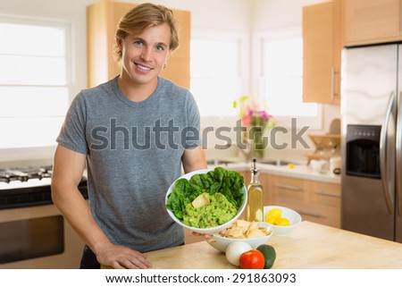 Home chef making a serving of guacamole with a charming smile young man in the kitchen