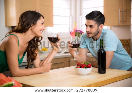 Male and female sipping red wine in the kitchen sharing a romantic gaze with chemistry