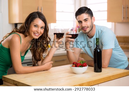 Pretty woman and handsome man portrait with some red wine at home indoors smiling
