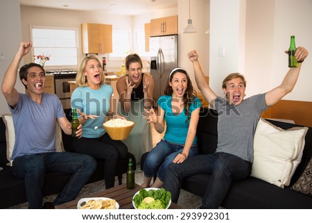 Sports fans at home watching the game on tv cheering for their team goal