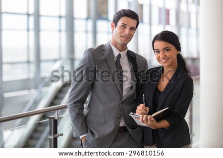 Business executive and assistant traveling at convention on a trip in the airport taking notes portrait