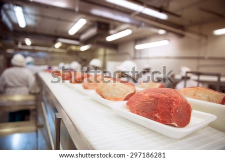 Factory row line of raw pork meat with workers at industrial factory