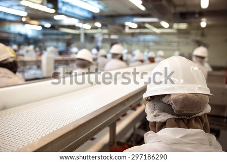 Factory workers grouped at working facility with safety gear and machinery