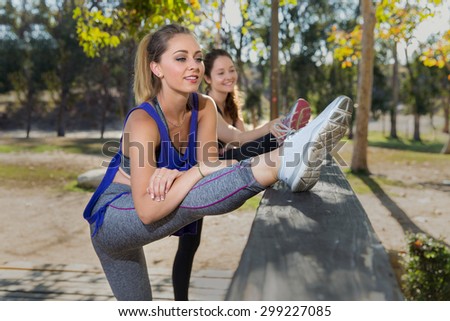 Two female joggers stretching routine warm up before a summer day cardio fitness exercise