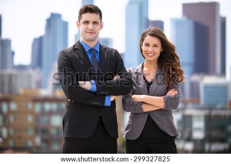 Portrait of handsome businessman and woman confident against downtown skyline buildings