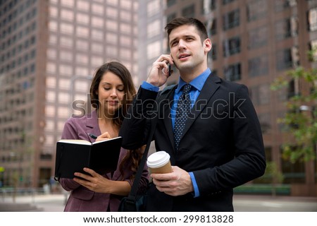 Business person CEO executive on cell phone walking near building with personal assistant