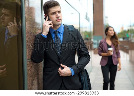 Man in suit blue shirt and tie next to building on a cell phone business attorney