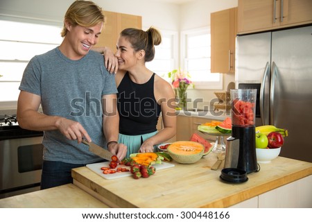 Young handsome beauty couple lovers dating make smoothie slicing fresh fruits and veggies