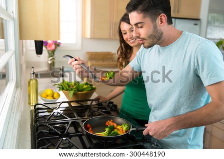 Couple cooks dinner together on stove hot food blows cool air before biting tasting