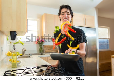 Cook handsome chef man flips tosses veggies on frying pan making dinner