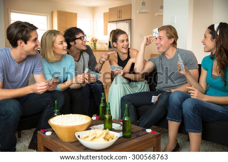 Group crowd of people friends at home in dorm playing games cards poker excited