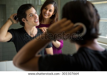 Man brushes thick head of hair in mirror smiling with girlfriend attractive no loss follicle