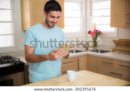 Man with smart tablet device reading the morning news with a  cup of coffee at home single male