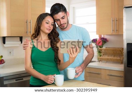 Endearing couple looking at videos online on a smart tablet sad emotional love sweet hug