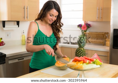 Beautiful model woman cutting fresh fruit organic vegan lifestyle vegetarian paleo nuts vegetables
