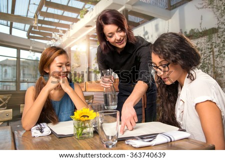 Waitress server helping client patron customer with menu order on sunny patio