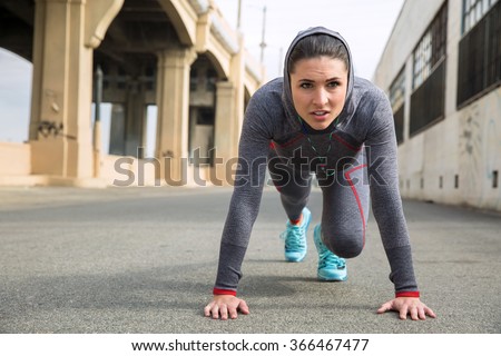 Strong athletic toned female athlete in sportswear with hoody training with push ups outdoors