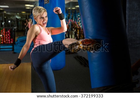 Woman kicks bag intense kickboxing muay thai training amateur beginner martial arts class