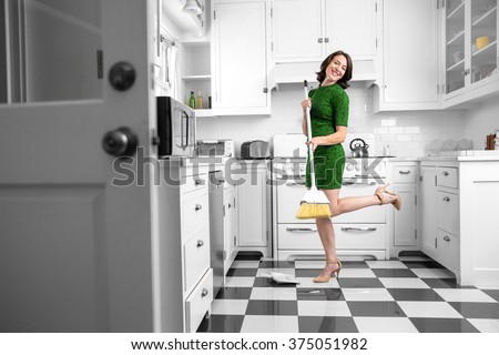Dancing fun lifestyle in the kitchen woman laughing playing while sweeping floor in heels