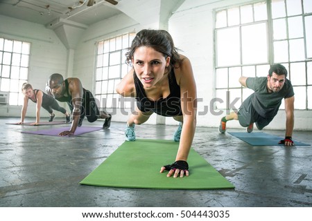 Strong powerful intense fit female leader of athletic fitness team exercising one arm push ups