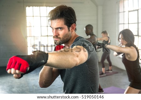Handsome masculine athlete boxer mma fighter training with fitness group punching aerobox