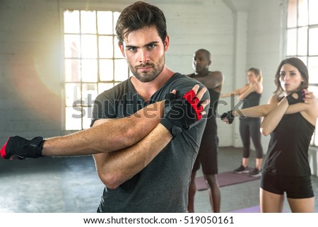 Intense focused man serious expression stretch before workout in group exercise gym