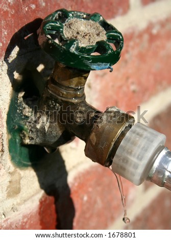 Dripping water spigot outside of house with hose attached
