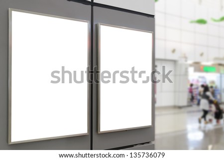 Two big vertical / portrait orientation blank billboard on wall in public open space with blurred shop background