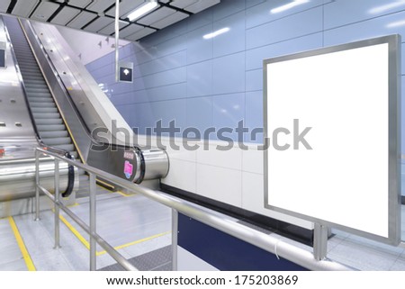 One big vertical / portrait orientation blank billboard in public transport with escalator and blurred passenger background