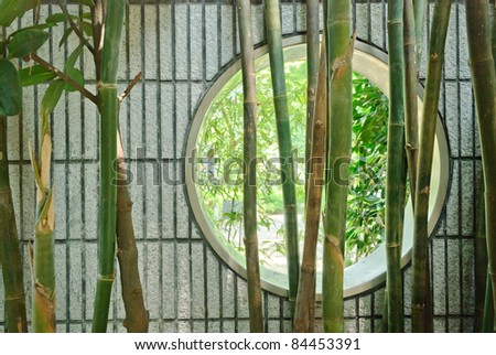 Round Chinese window in wall in garden with bamboo
