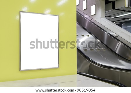 One big vertical / portrait orientation blank billboard on modern yellow wall with escalator background