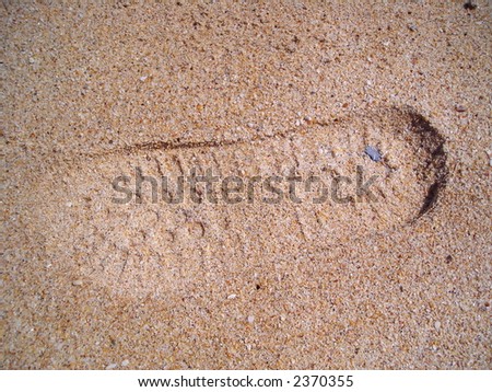 A shoe print imprinted on the sand.