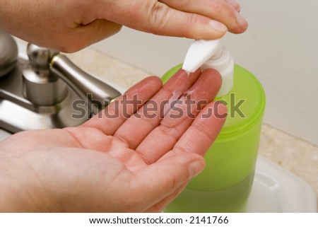 woman washing hand under running water white sink chrome spout putting liquid soap on hands
