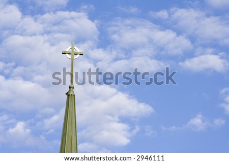 blue cloud filled sky with a cross from a church in the sky