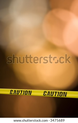 Yellow tape with the word caution on it across a warning light background