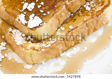 french toast on a white plate with powdered sugar and maple syrup