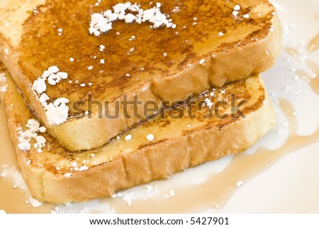french toast on a white plate with powdered sugar and maple syrup