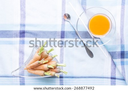 Baby carrots juice glass with raw ingredient on blue table mat