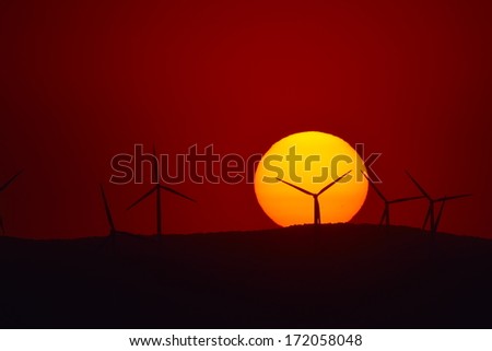 beautiful sunset with wind turbines silhouettes on the hill