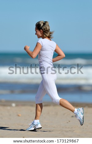 young healthy woman jogging on the beach in summer