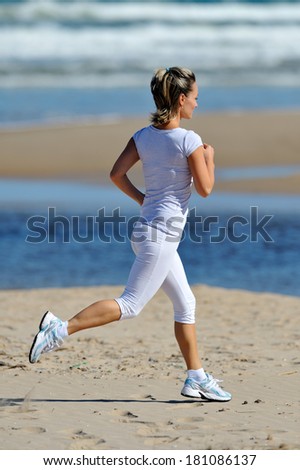 young woman jogging on the beach in summer sunny day