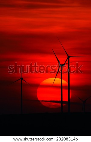 beautiful sunset with wind turbines on the hill in summer, silhouettes