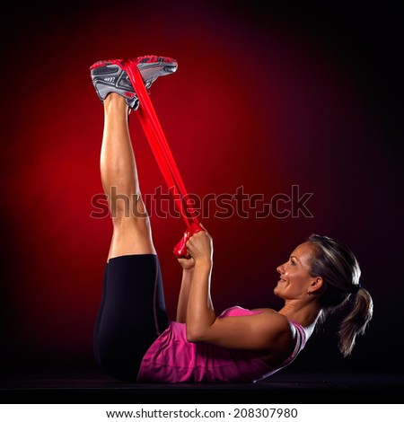 young woman exercising with elastic fitness band in the gym