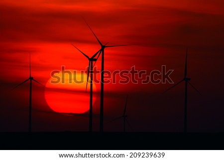 beautiful sunset with wind turbines silhouettes on the hill in summer