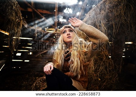Beautiful woman relaxing in straw in autumn in smoky, dusty room