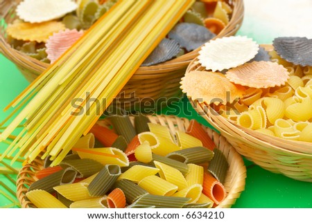 asorted uncooked pasta in baskets on green background
